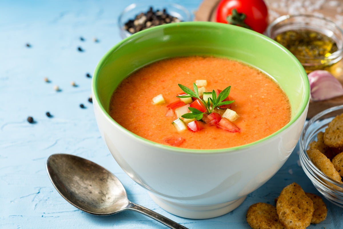 A colorful bowl of gazpacho soup garnished with chopped vegetables