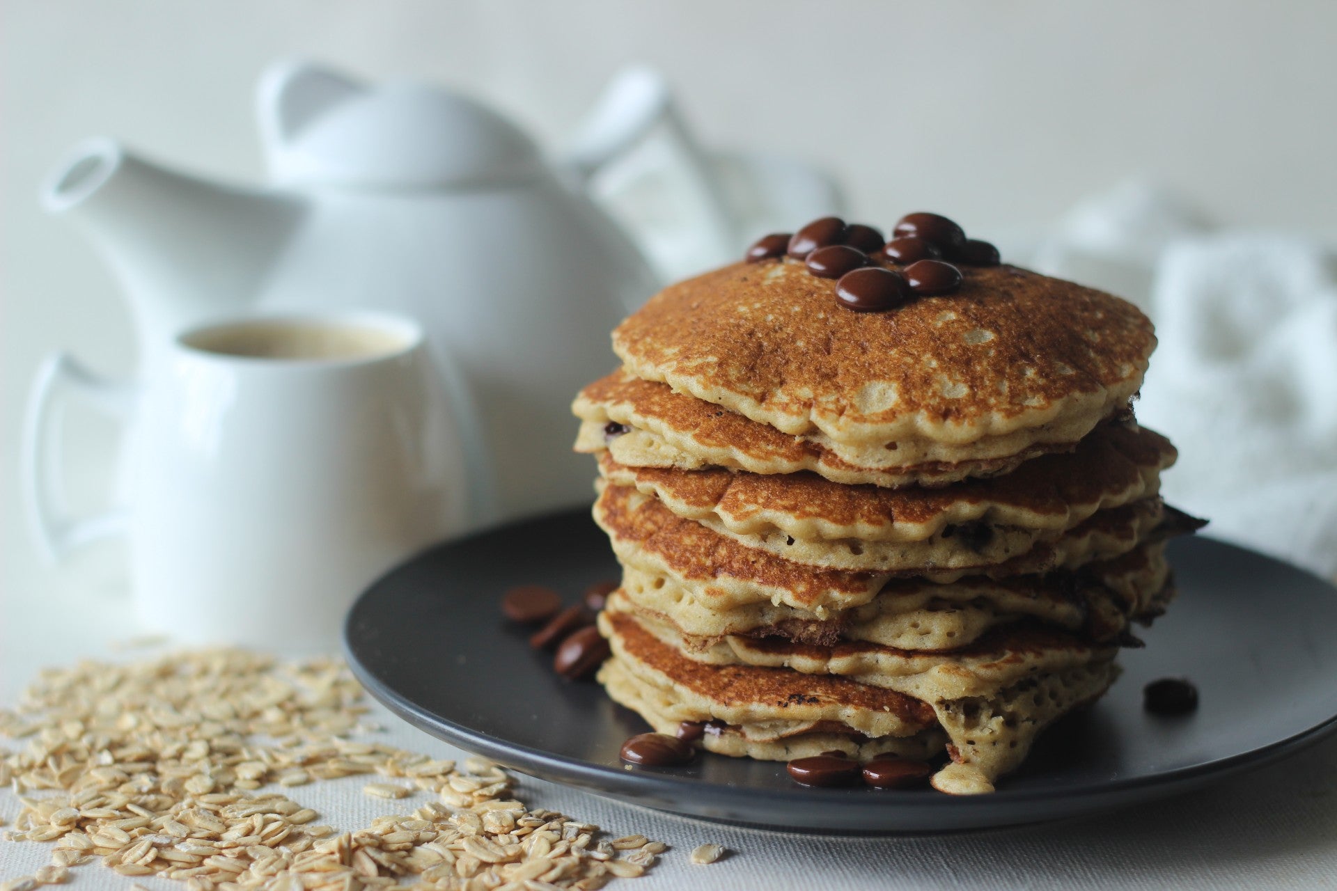 Stack of golden oatmeal pancakes accompanied by syrup
