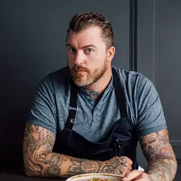Chef Gus Stieffenhofer-Brandson seated with a plate of food.