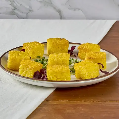 Yellow risotto al sato bites on a plate.