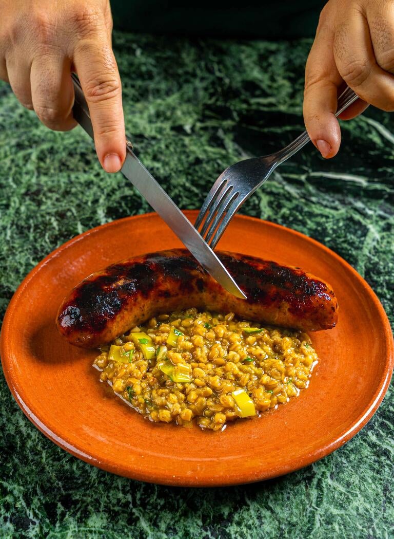 Sausage and corn on an orange plate at Gia Vin &amp; Grill.