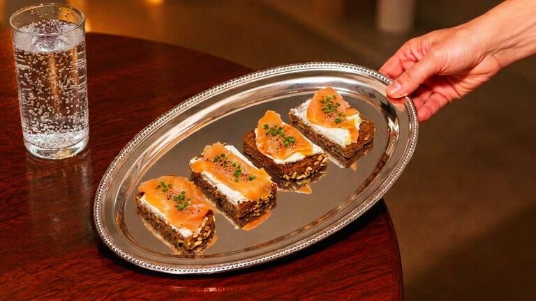 Rye bread canapés with marinated salmon and aromatic herbs.
