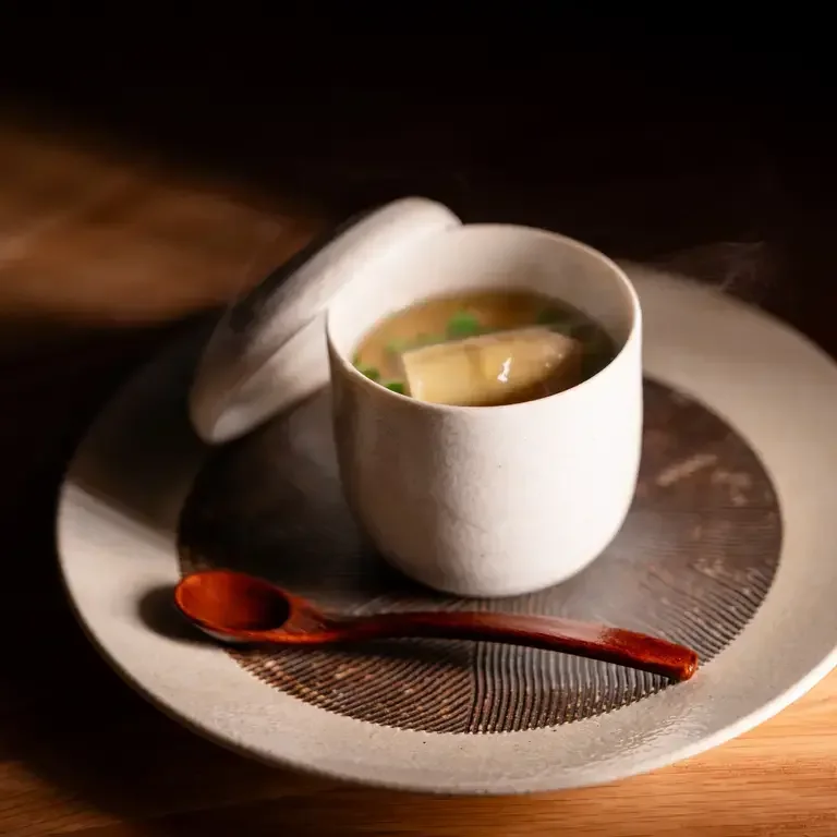 Bowl of broth with a wooden spoon at Sen.