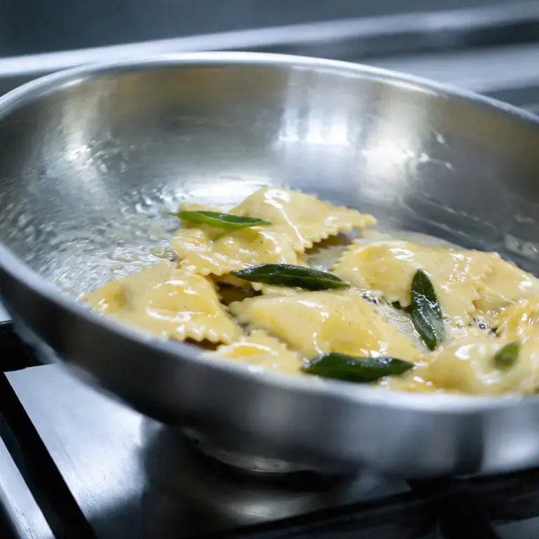 A pan of ravioli with butter and sage.