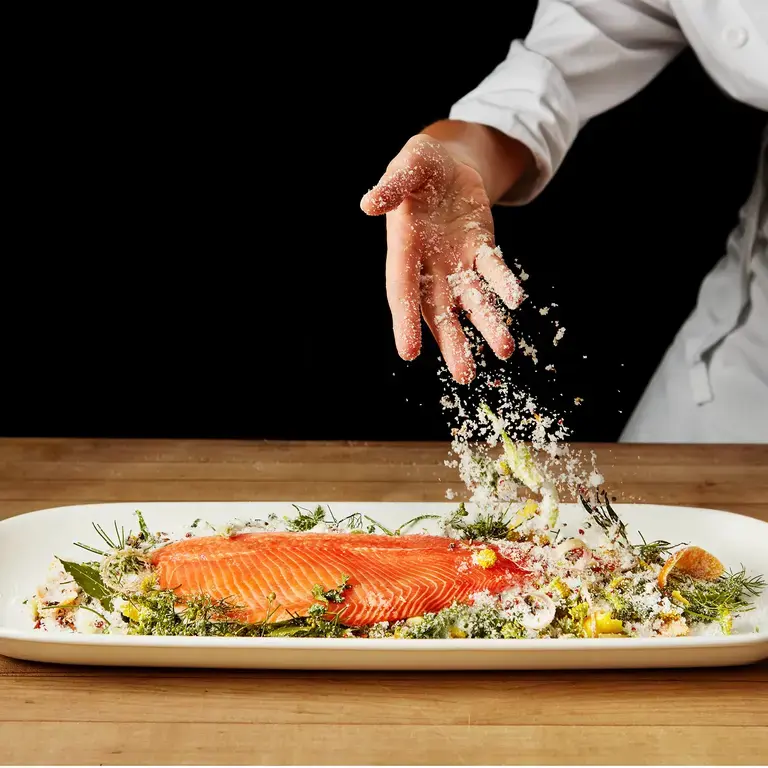 A chef curing a piece of salmon.