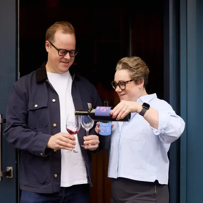 Pascal and Laura Wiedemann pouring wine outside Pompette.