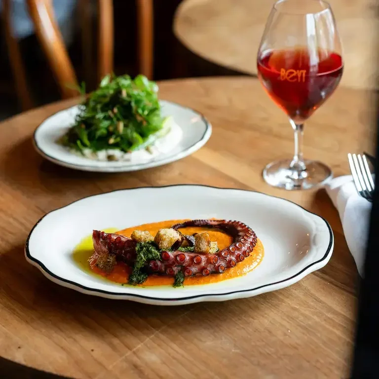 Two dishes and a glass of wine on a table at Beyt Cave à Manger.