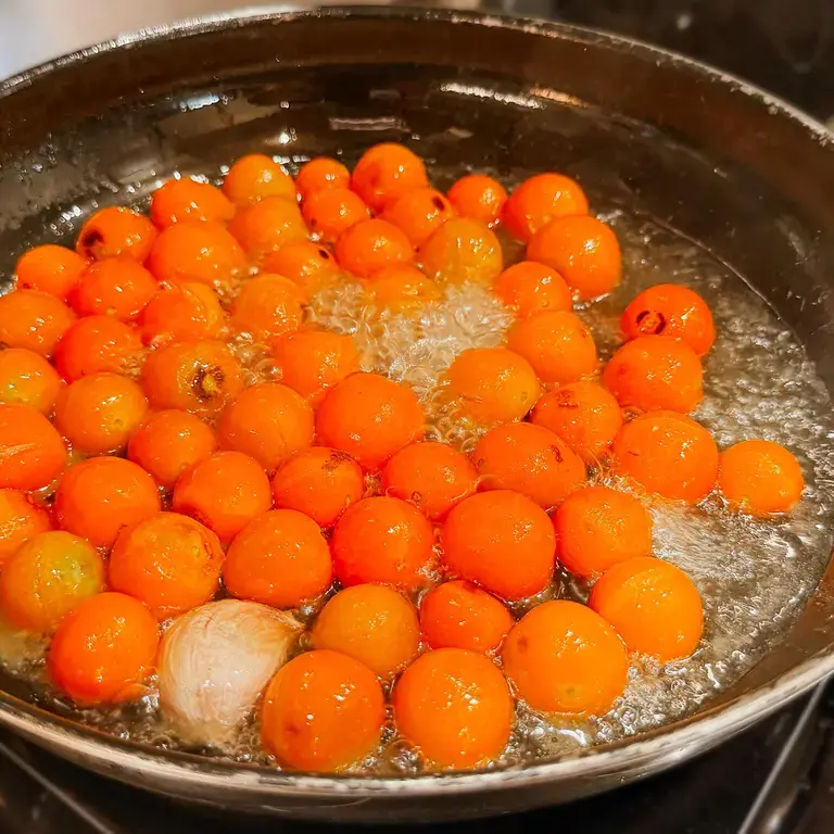 Confit yellow datterini tomatoes in a metal pan.