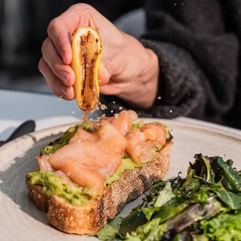 Squeezing citrus over fish and avocado on toast at Mood.