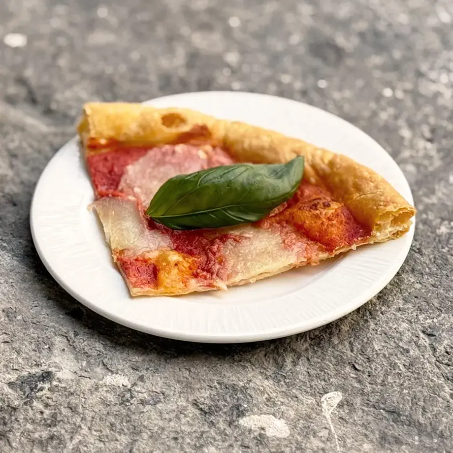 Slice of puff pastry pizza with tomato and pesto.