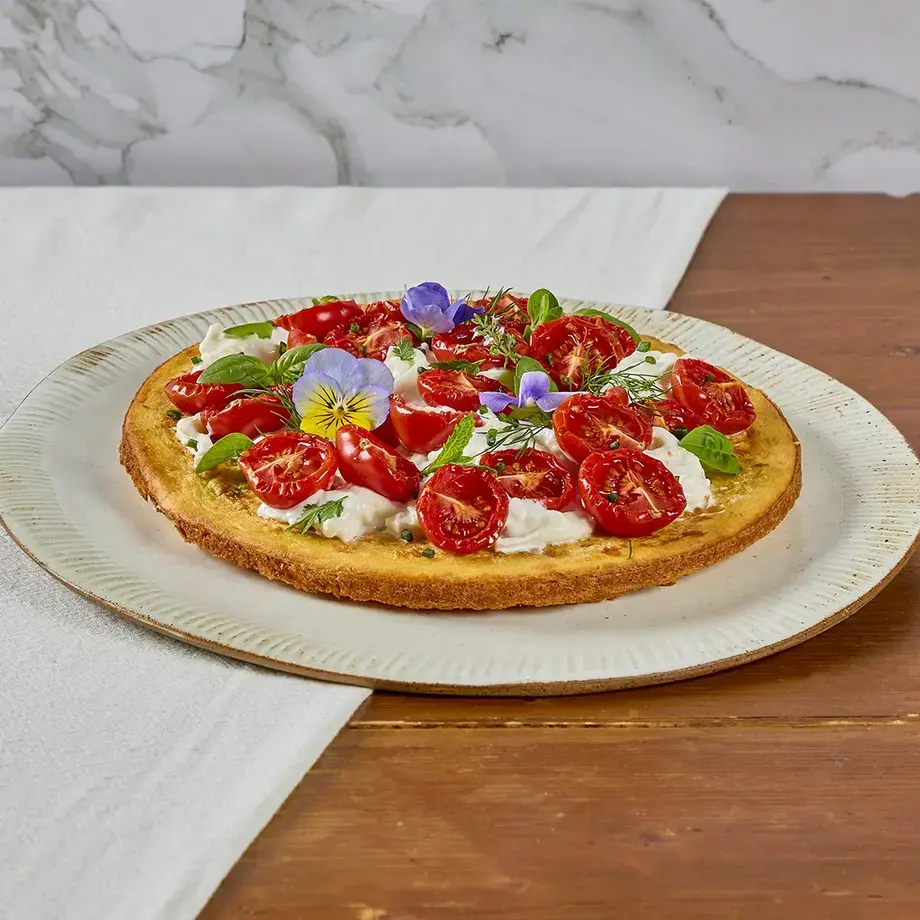 Crispy socca with stracciatella, confit tomatoes and Mediterranean herbs..