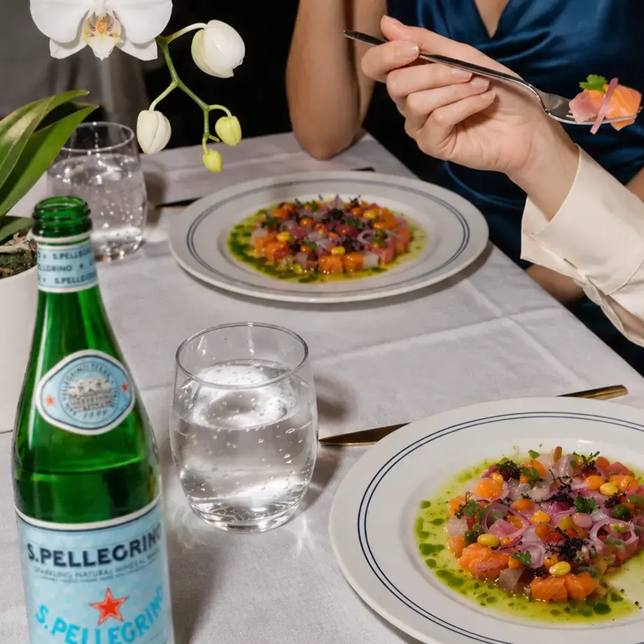 Plates of ceviche on a restaurant table with S.Pellegrino.