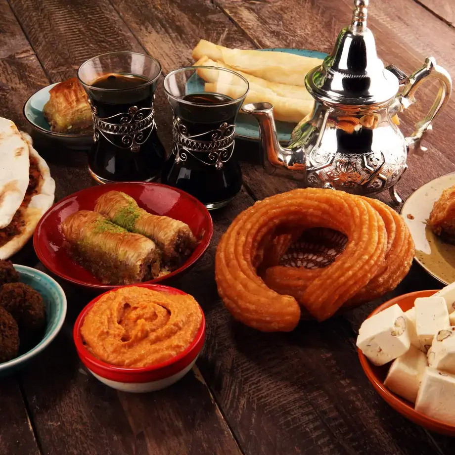 A table of halal food including sweet and savory snacks and black tea