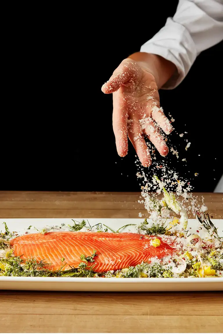 A chef curing a piece of salmon.