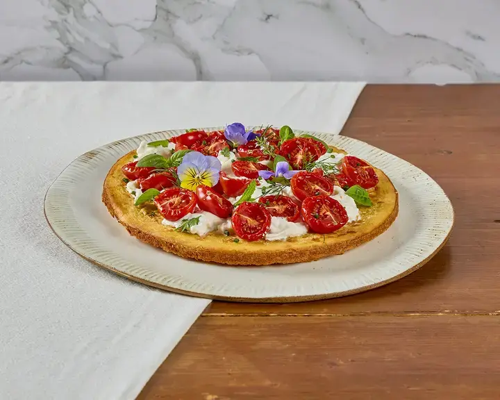 Crispy socca with stracciatella, confit tomatoes and Mediterranean herbs..