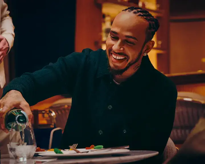 Lewis Hamilton pouring S.Pellegrino into a glass.
