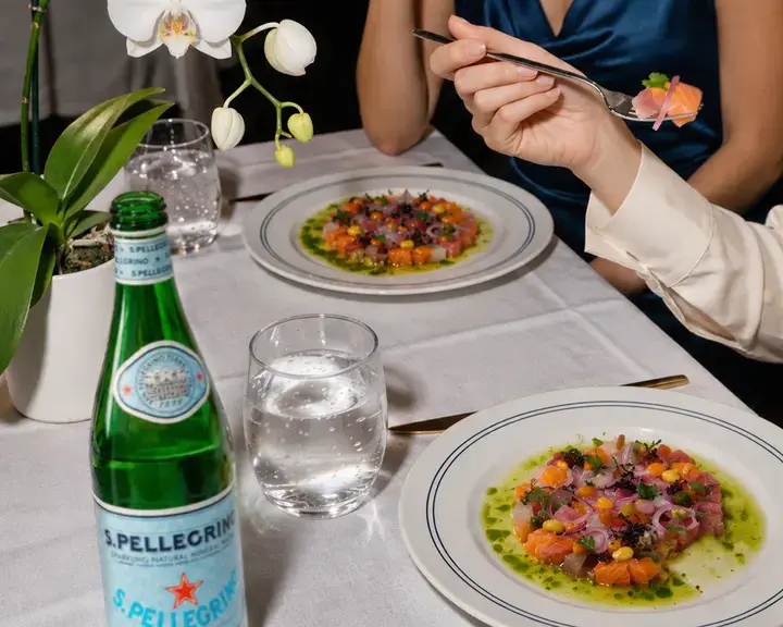 Plates of ceviche on a restaurant table with S.Pellegrino.